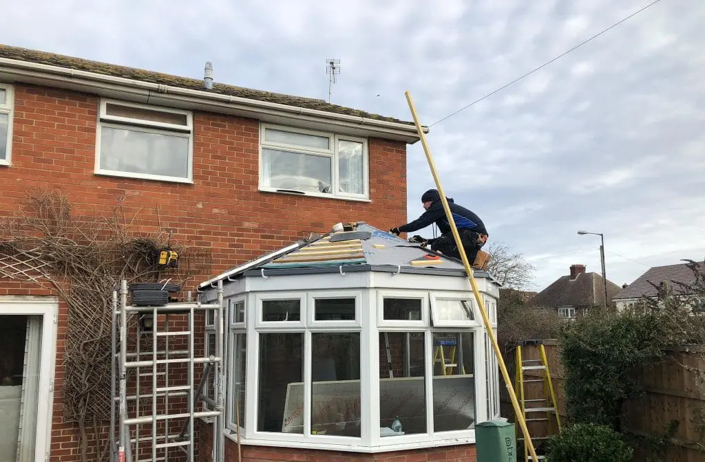 Staff from Nu-Look Conservatory Roof Solutions standing on conservatory roof, fitting a new solid roof.