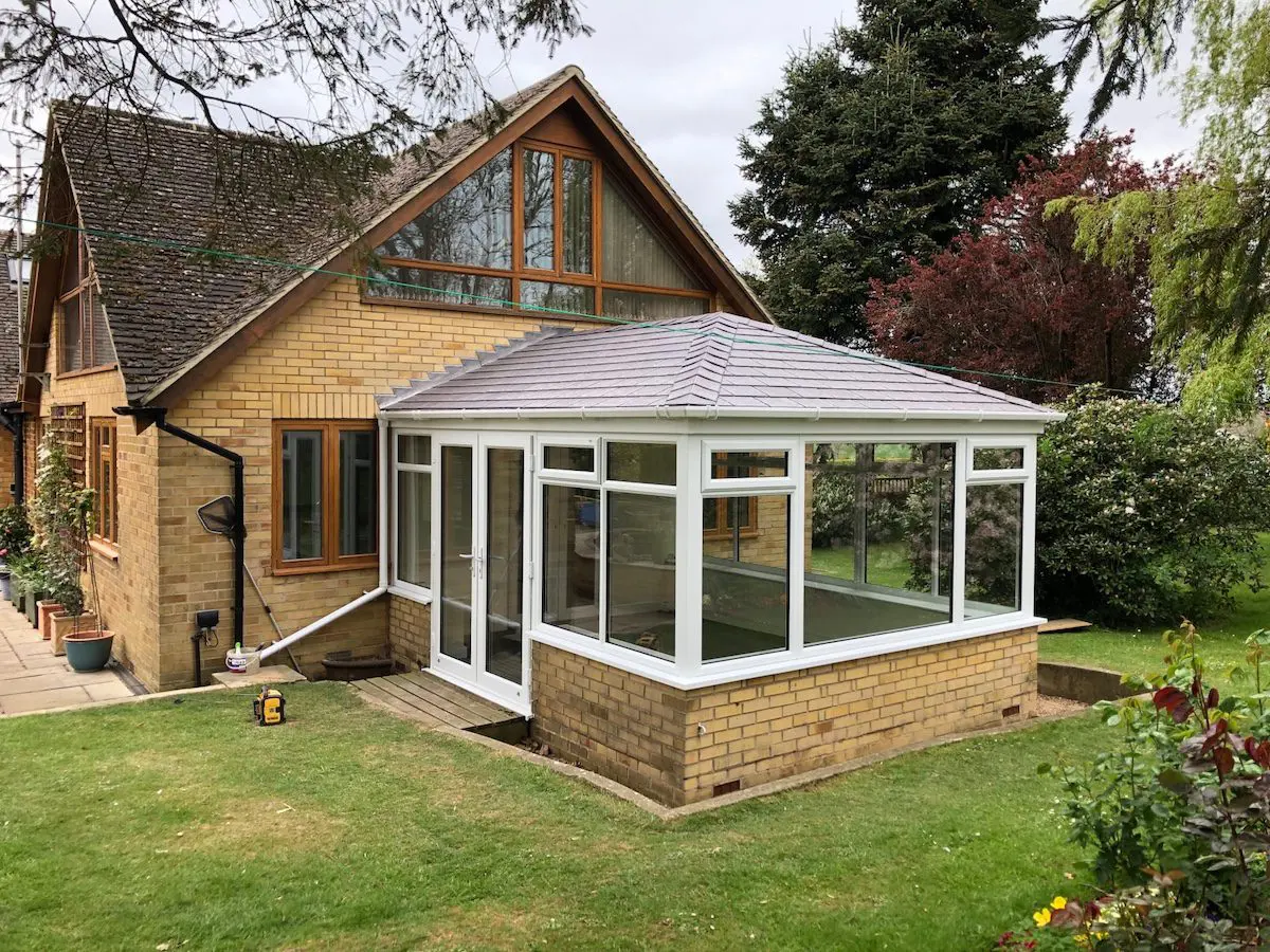 Conservatory with tiled roof attached to a brick house, illustrating poor insulation and heat loss.
