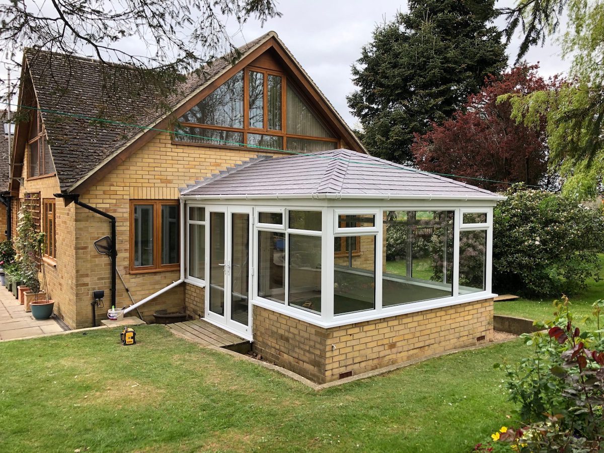Conservatory with tiled roof attached to a brick house, illustrating poor insulation and heat loss.