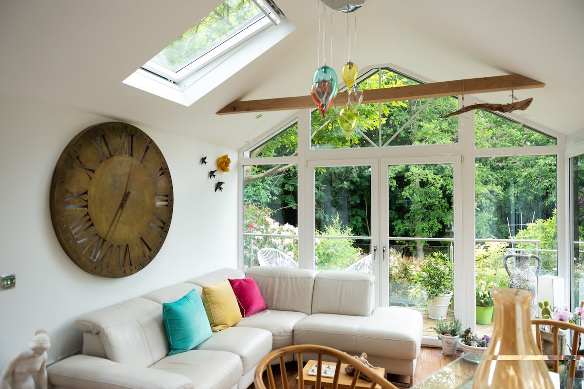 Modern conservatory interior with skylight, insulated roof and comfortable seating for year-round use